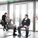 Veronika Egger und Fritz Frenkler testen einen Sessel und diskutieren über die Sitzqualitäten. In Hintergrund Verena Voppivhler.